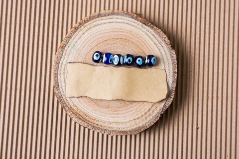 Evil eye beads and piece of burnt paper on wood log