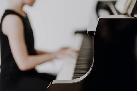 Elegant girl sits at the concert grand and plays the piano