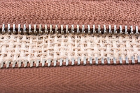 Parts of the brown color zipper on linen canvas background