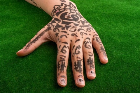 Hand with tattoo on green grass