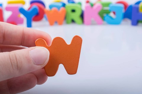 Hand holding letter cube W of made of wood