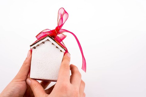 Hand holding a model house with a pink ribbon