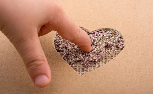 Hand on heart shape hole on paper on the linen canvas