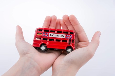Hand holding a London double decker bus on a white background