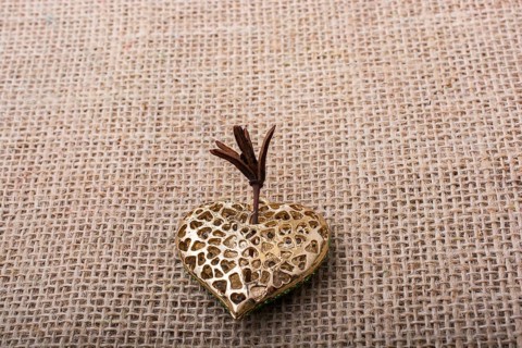 Heart shaped gold color metal object on canvas