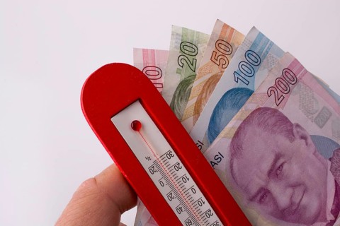 Turkish Lira banknotes by the side of a red color temperature on white background