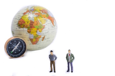 A couple by the side of a globe with a compass on isolated white background