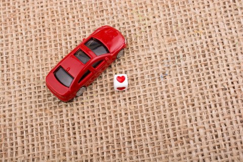 Love cube on a red toy car on a linen canvas