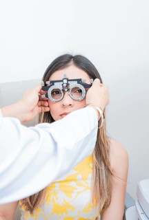 Doctor adjusting vision of patient with optometrist trial frame. ophthalmologist examining girl with optometrist trial frame