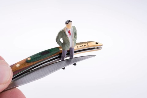 Hand holding a pocket knife near a human figure on a white background