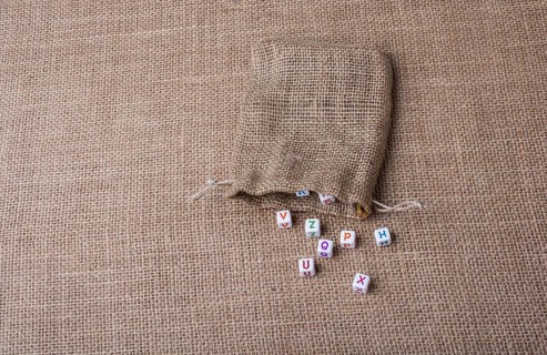 Colorful alphabet letter cubes out of sack on a canvas