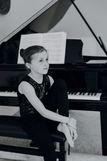 Elegant girl sits at the concert grand and plays the piano