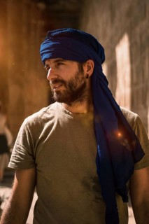 A young tourist in a blue turban visiting the Edfu Temple in the morning near Aswan city. Egypt