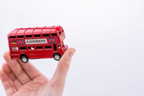 Hand holding a London double decker bus on a white background