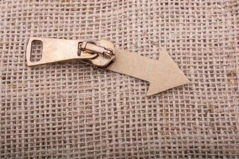 Arrow sign cut out of paper with zipper on canvas