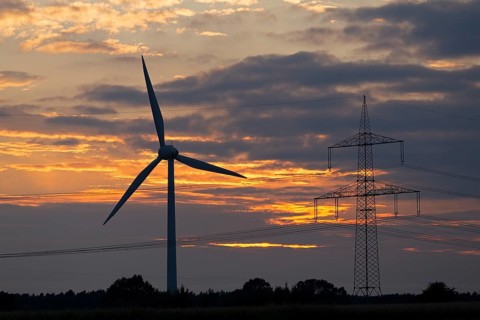 Wind power station and high voltage pylon in front of evening sky