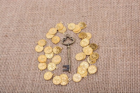 Hand holding a retro styled key over fake gold coins