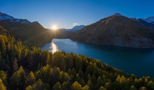 Aerial view at sunset over the autumnal forest at Lago di Luzzone in Valle di Blenio