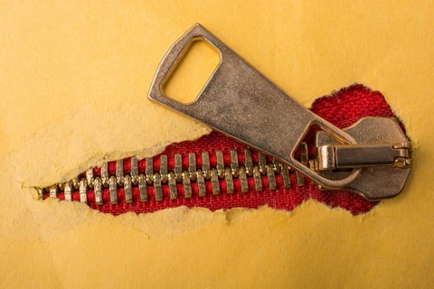 Torn paper with hole on a colorful zipper