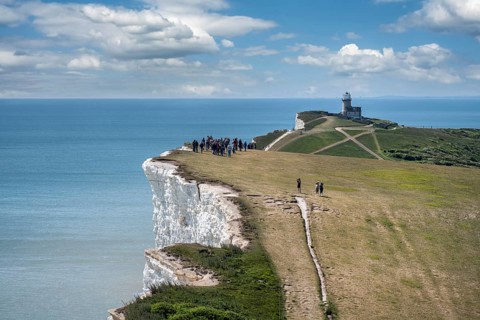 Tourists walking along the chalk cliffs at Beachy Head