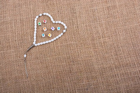 Heart shaped cubes in hand by inside a praying beads