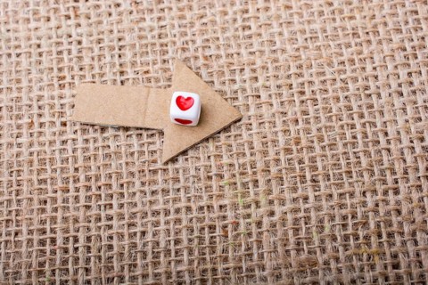 Love cubes on arrow cut out of brown paper on canvas
