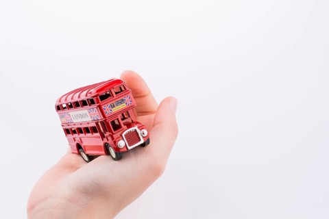Hand holding a London double decker bus on a white background