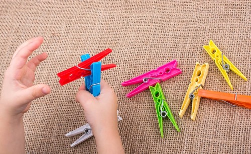 Color clothespin in hand on a linen canvas background