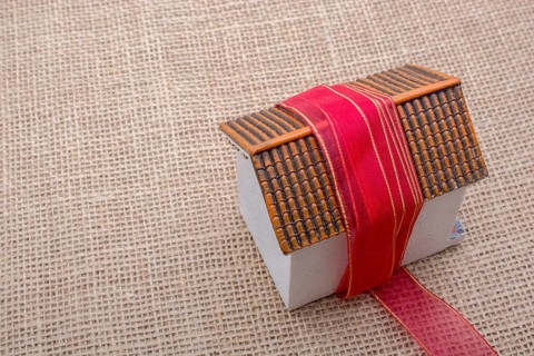 Pink band wrapped around a model house on a brown background