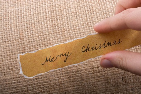 Merry Christmas wording written on a torn paper in hand