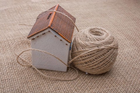 Thread wrapped around a model house on a brown background