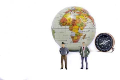 A couple by the side of a globe with a compass on isolated white background