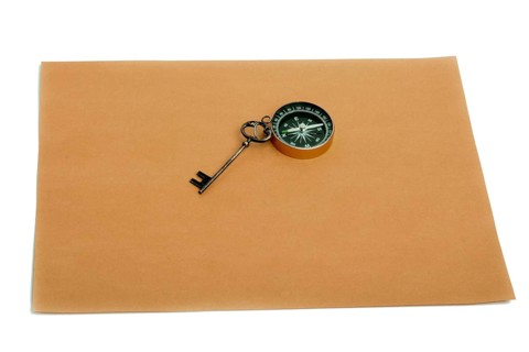 Key and compass on a sheet of colored plain paper with a white background