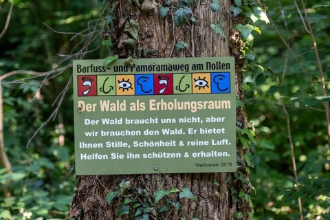 Sign The forest as a recreational space on a tree stump on the Wuppenau barefoot path on the Nollen