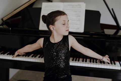 Elegant girl sits at the concert grand and plays the piano