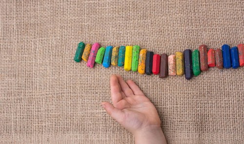 Toddlers hand putting crayons in line on canvas