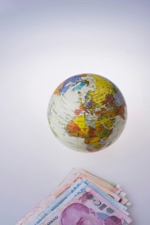 Turkish Lira banknotes by the side of a model globe on white background