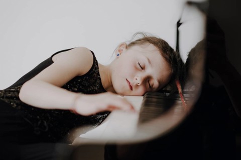 Elegant girl sits at the concert grand and plays the piano