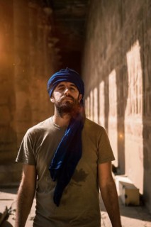 A young tourist in a blue turban visiting the Edfu Temple in the morning near Aswan city. Egypt