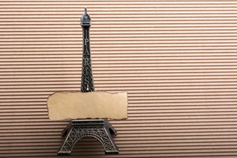 Burnt piece of paper on model Eiffel tower on cardboard