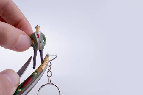 Hand holding a pocket knife near a human figure on a white background