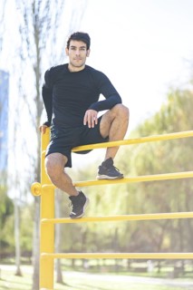 Young man posing after doing climbing vertical exercise in the park