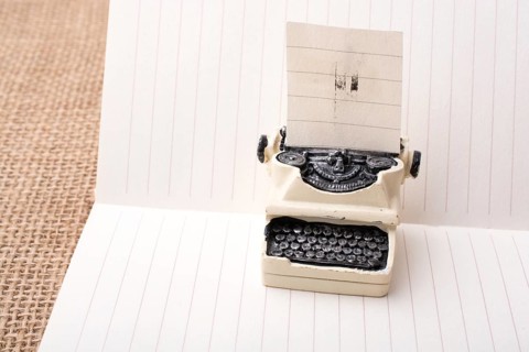 Retro syled tiny typewriter model on a paper background
