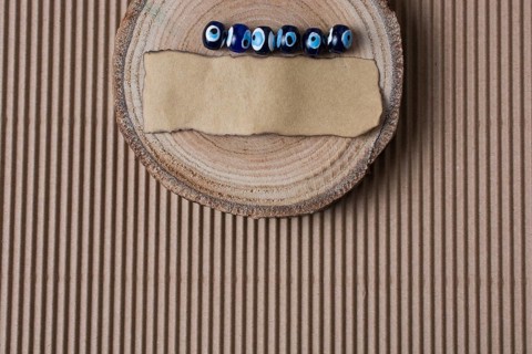 Evil eye beads and piece of burnt paper on wood log
