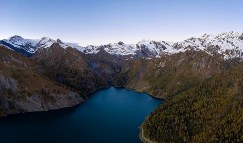 Aerial view over Lago di Luzzone with the snow-covered mountain peaks in the background