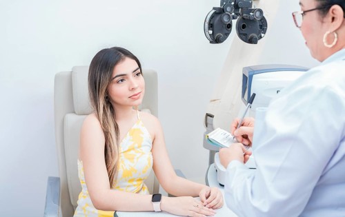 Female patient having consultation with optometrist in office. Optometrist with female patient taking notes in office