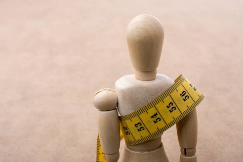Yellow color measuring tape wrapped on wooden man