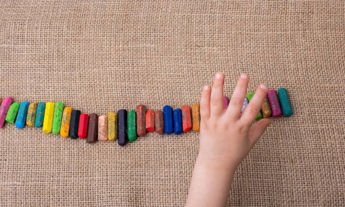 Toddlers hand putting crayons in line on canvas