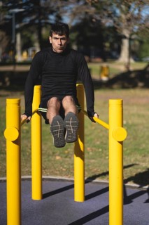 Fit young man doing push ups on horizontal bar outdoors