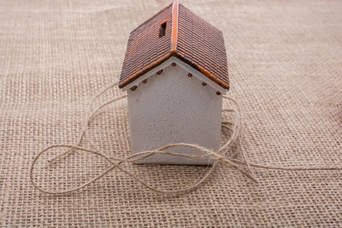 Thread wrapped around a model house on a brown background